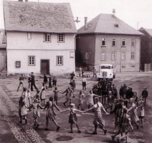 Die Aufnahme von ca. 1952 zeigt links das Ebersgönser Backhaus. Das Obergeschoss diente nach 1945 einige Zeit als Schulraum. Rechts die 1846 gebaut Schule. Heute ist es kaum noch vorstellbar, dass einst um das Backhaus die Kinder ungestört in der Schulpause spielen konnten. 