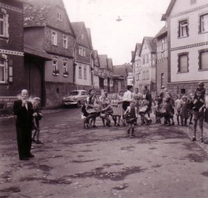 Schulpause für die Kinder und Zigarettenpause für den Lehrer um 1952 im Dorfmittelpunkt von Ebersgöns neben der Schule und dem Backhaus.